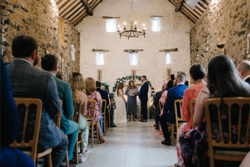 Guests watching a wedding ceremony in a stone barn venue