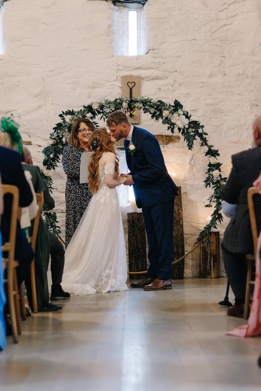 Couple sharing their first kiss under a greenery arch