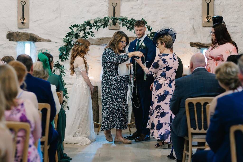 Wedding ceremony under a greenery arch in a stone venue in North Wales