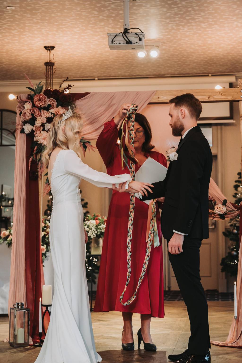 Celebrant and a newly married couple celebrating under a floral arch