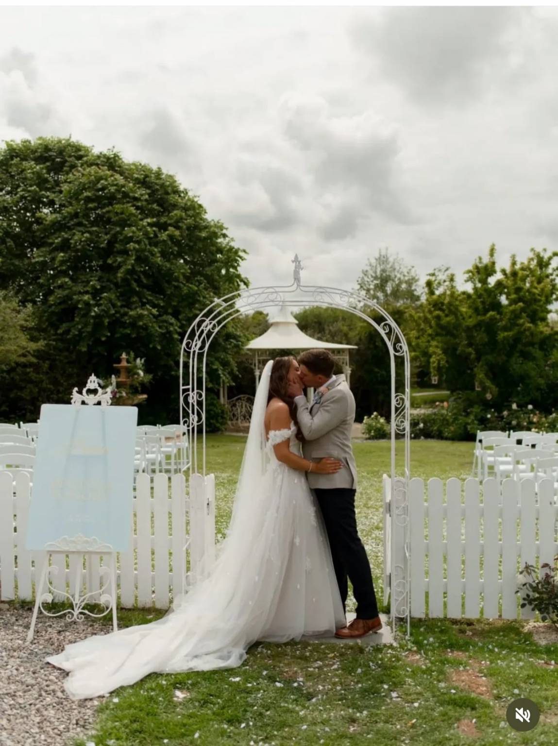 Couple kissing under a white wedding arch